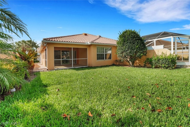 7933 Umberto Ct, Naples, FL 34114 - rear view of property with glass enclosure, stucco siding, a tiled roof, and a yard