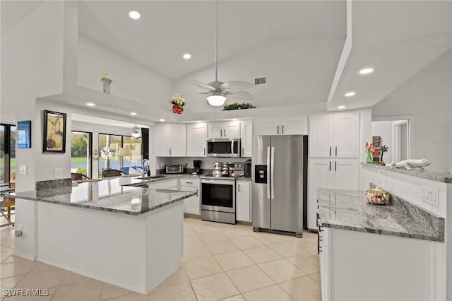 kitchen featuring white cabinets, a peninsula, light stone countertops, appliances with stainless steel finishes, and a sink