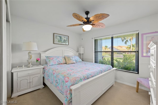 bedroom with a ceiling fan, baseboards, and light colored carpet