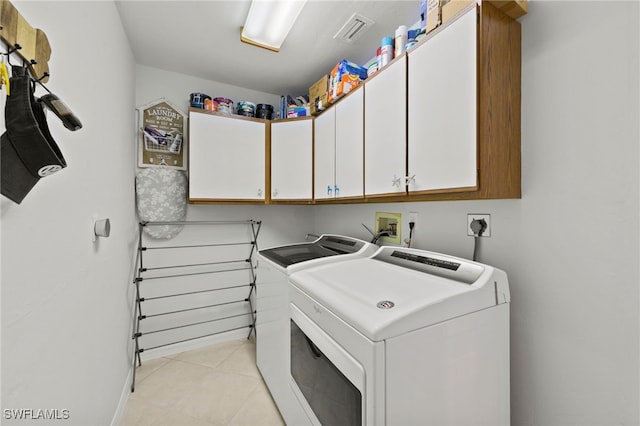 clothes washing area with light tile patterned floors, cabinet space, washer and clothes dryer, and visible vents