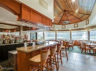 bar featuring visible vents, wooden ceiling, lofted ceiling, and light tile patterned floors