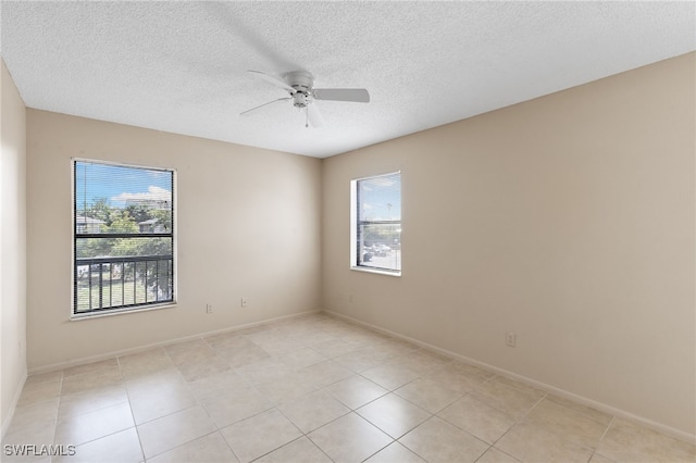 spare room with a textured ceiling, ceiling fan, baseboards, and light tile patterned floors