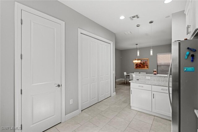 1338 Kendari Ter, Naples, FL 34113 - kitchen with light tile patterned floors, freestanding refrigerator, a peninsula, white cabinetry, and pendant lighting