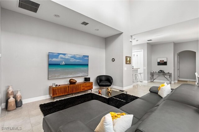 1338 Kendari Ter, Naples, FL 34113 - tiled living room with arched walkways, visible vents, baseboards, and a high ceiling