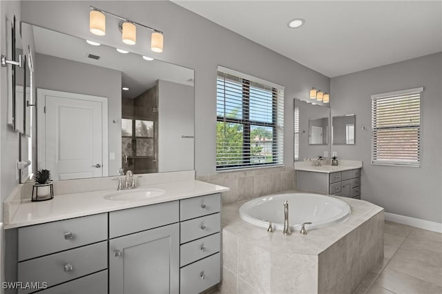 1338 Kendari Ter, Naples, FL 34113 - bathroom with two vanities, a sink, tile patterned flooring, a healthy amount of sunlight, and a garden tub