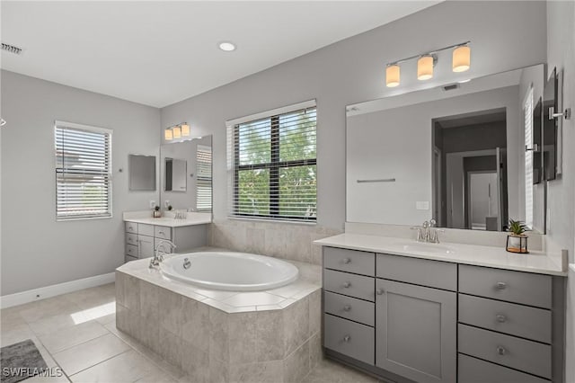 1338 Kendari Ter, Naples, FL 34113 - bathroom featuring visible vents, a bath, a sink, two vanities, and tile patterned flooring