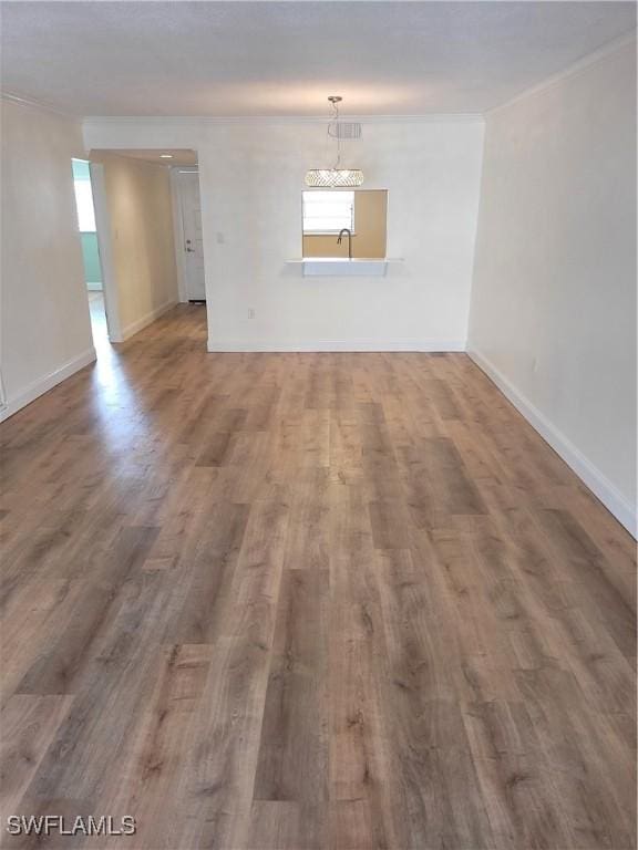 unfurnished room featuring a sink, ornamental molding, a wealth of natural light, and wood finished floors