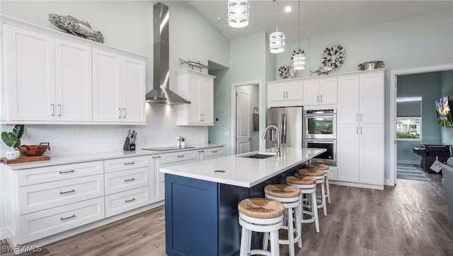 162 Windward Cay, Naples, FL 34114 - kitchen with wall chimney exhaust hood, a sink, white cabinetry, stainless steel appliances, and a breakfast bar area