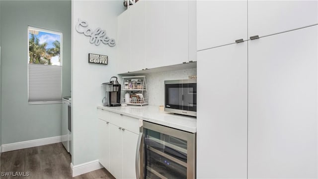 162 Windward Cay, Naples, FL 34114 - bar featuring dark wood-type flooring, stainless steel microwave, wine cooler, baseboards, and backsplash