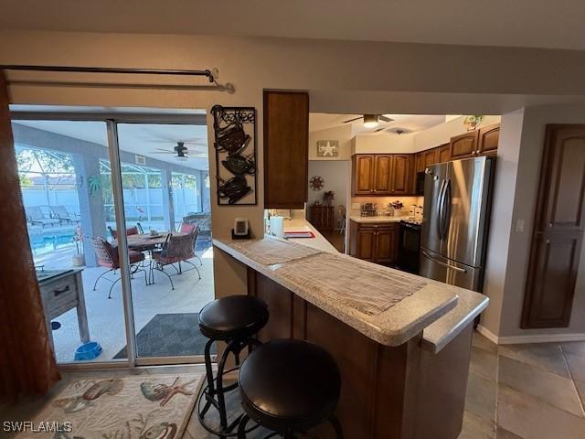 408 SE 19th Ln, Cape Coral, FL 33990 - kitchen featuring light countertops, a kitchen bar, freestanding refrigerator, a ceiling fan, and a peninsula