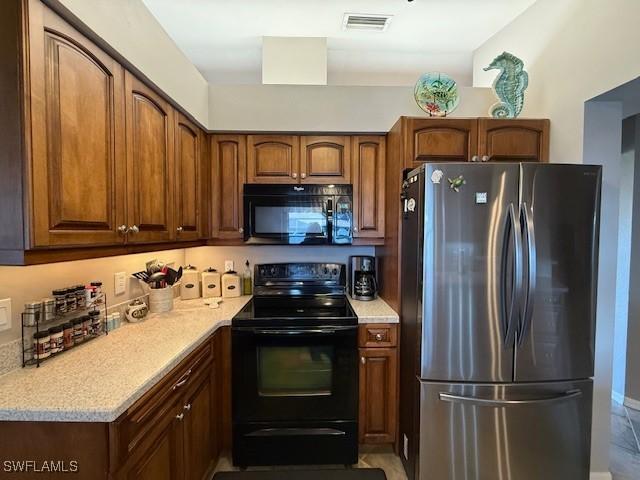 408 SE 19th Ln, Cape Coral, FL 33990 - kitchen with visible vents, black appliances, light countertops, and brown cabinetry