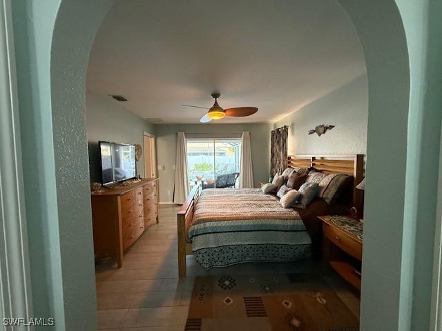 408 SE 19th Ln, Cape Coral, FL 33990 - bedroom featuring arched walkways, access to exterior, visible vents, a ceiling fan, and wood finished floors