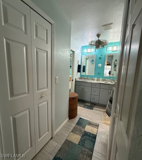 408 SE 19th Ln, Cape Coral, FL 33990 - bathroom with wood finish floors, a textured ceiling, a sink, visible vents, and double vanity