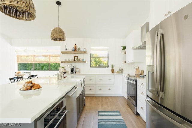 167 1st St, Bonita Springs, FL 34134 - kitchen with light countertops, open shelves, white cabinetry, wall chimney exhaust hood, and stainless steel appliances