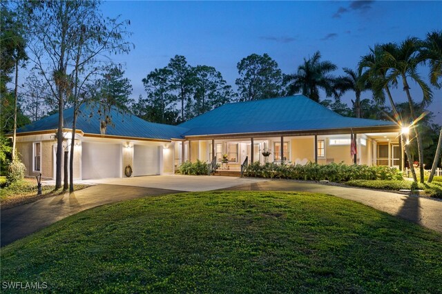 5660 English Oaks Ln, Naples, FL 34119 - ranch-style house featuring stucco siding, metal roof, a front yard, concrete driveway, and an attached garage