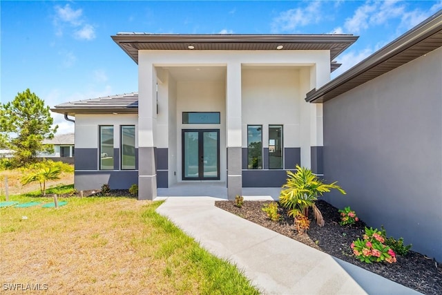 doorway to property featuring a lawn, stucco siding, and french doors