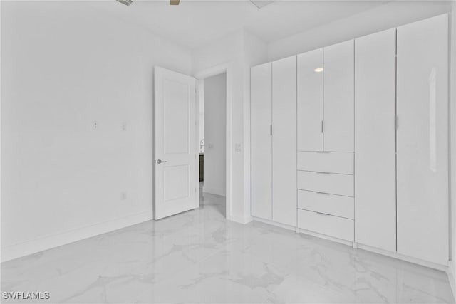 unfurnished bedroom featuring baseboards and marble finish floor