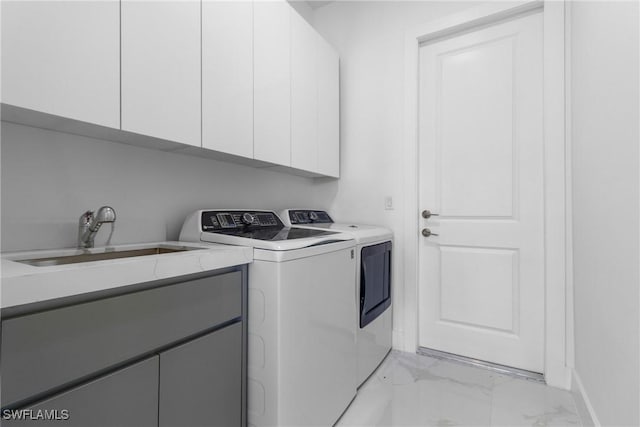clothes washing area featuring cabinet space, a sink, separate washer and dryer, marble finish floor, and baseboards