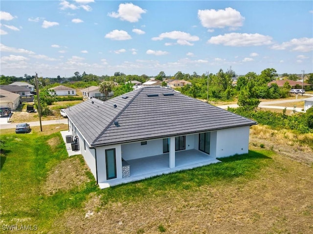 back of property featuring a yard, a patio, and stucco siding