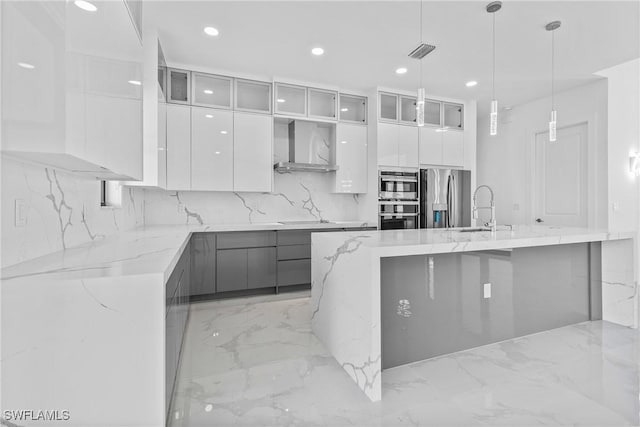 kitchen featuring marble finish floor, modern cabinets, wall chimney exhaust hood, a sink, and stainless steel appliances