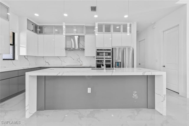 kitchen featuring visible vents, marble finish floor, modern cabinets, wall chimney range hood, and appliances with stainless steel finishes