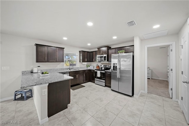 kitchen featuring dark brown cabinetry, a sink, appliances with stainless steel finishes, a peninsula, and visible vents