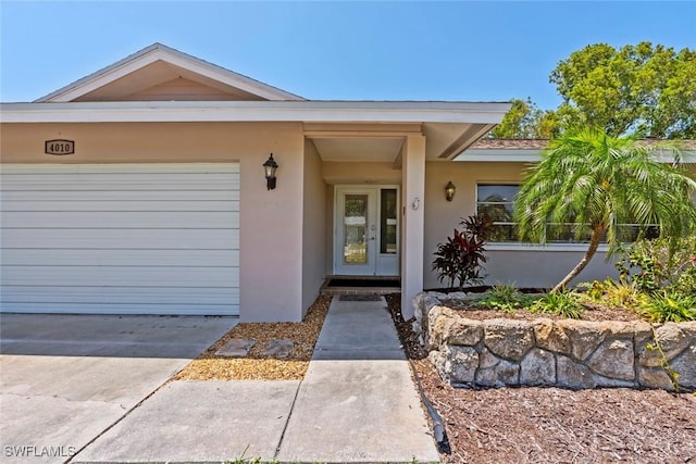 view of exterior entry featuring a garage and stucco siding