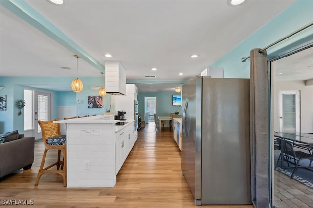 kitchen with white cabinets, freestanding refrigerator, a peninsula, recessed lighting, and light wood-style flooring
