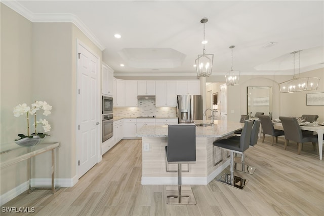 28091 Foxrock Ct, Bonita Springs, FL 34135 - kitchen featuring a kitchen breakfast bar, a chandelier, a tray ceiling, decorative backsplash, and stainless steel appliances