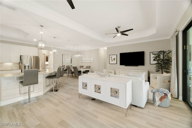 28091 Foxrock Ct, Bonita Springs, FL 34135 - living room featuring crown molding, a tray ceiling, light wood-type flooring, and ceiling fan with notable chandelier