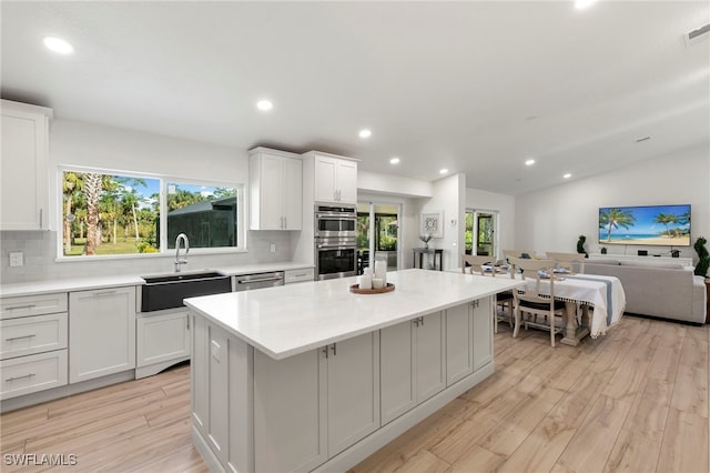 1020 19th St SW, Naples, FL 34117 - kitchen with light wood-style flooring, stainless steel appliances, tasteful backsplash, a kitchen island, and recessed lighting