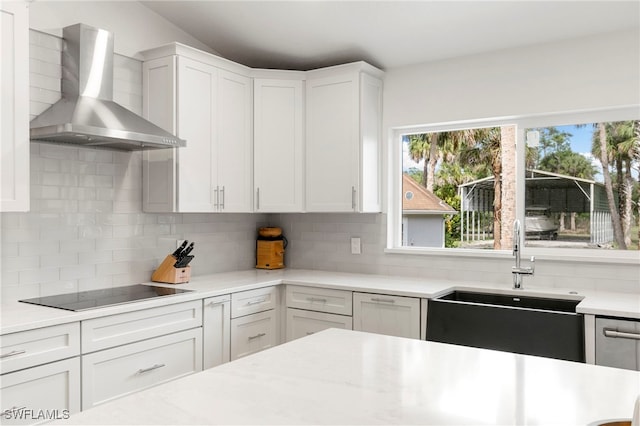 1020 19th St SW, Naples, FL 34117 - kitchen with wall chimney exhaust hood, black electric cooktop, decorative backsplash, light countertops, and white cabinetry