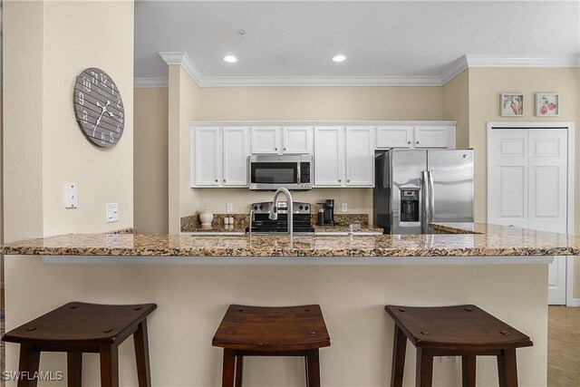 9815 Giaveno Ct Unit 1245, Naples, FL 34113 - kitchen with appliances with stainless steel finishes, crown molding, light stone countertops, a breakfast bar, and recessed lighting