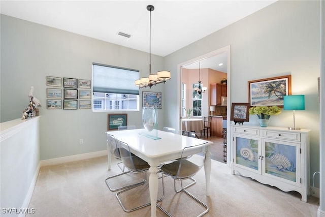 dining area featuring light carpet, visible vents, baseboards, and an inviting chandelier