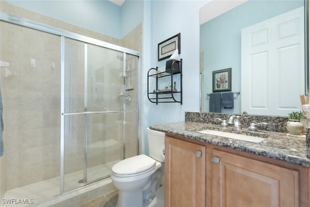 bathroom featuring toilet, a stall shower, vanity, and tile patterned flooring