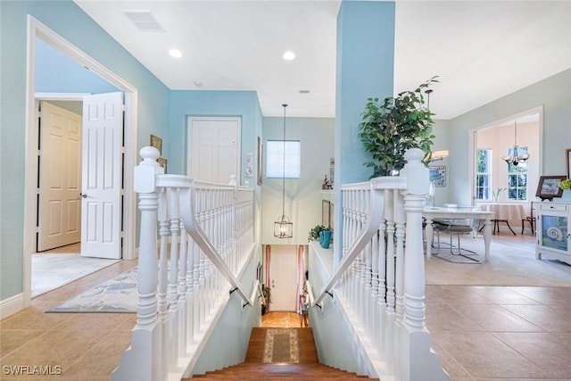 stairway featuring tile patterned floors, baseboards, visible vents, and a wealth of natural light