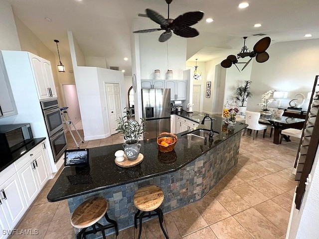 940 SE 20th Ct, Cape Coral, FL 33990 - kitchen with high vaulted ceiling, dark stone counters, stainless steel appliances, a sink, and ceiling fan with notable chandelier