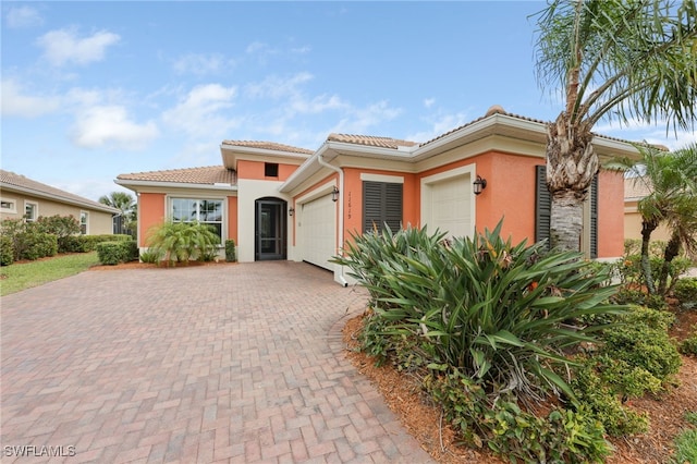 11619 Giulia Dr, Fort Myers, FL 33913 - view of front of home with a tile roof, stucco siding, decorative driveway, and a garage