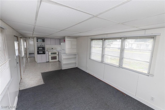 17841 Palm Creek Dr, North Fort Myers, FL 33917 - unfurnished living room with dark carpet, a healthy amount of sunlight, and a drop ceiling