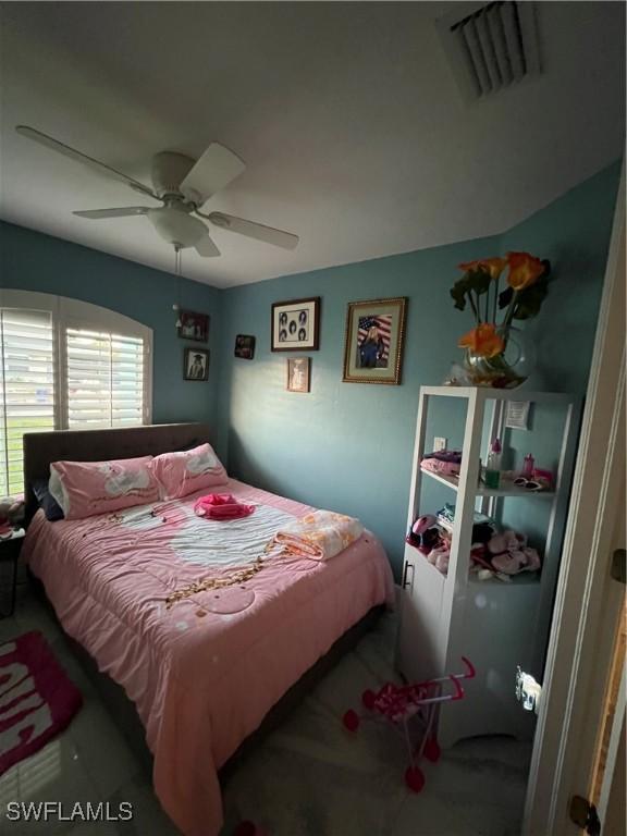 carpeted bedroom with a ceiling fan and visible vents