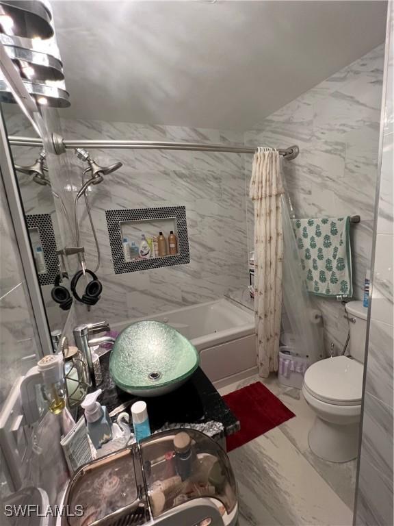 bathroom featuring toilet, tile walls, shower / bathtub combination with curtain, and marble finish floor