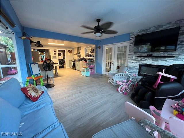 living room with wood finished floors, french doors, a fireplace, and ceiling fan