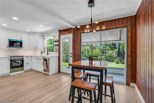 kitchen with light wood-style flooring, decorative backsplash, appliances with stainless steel finishes, light countertops, and a sink