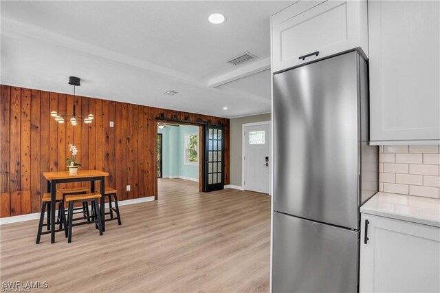 kitchen featuring visible vents, decorative backsplash, freestanding refrigerator, and white cabinetry