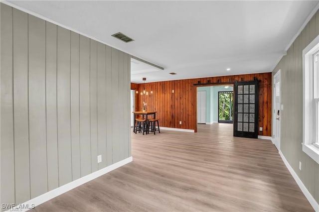 empty room featuring visible vents, wood walls, wood finished floors, and baseboards