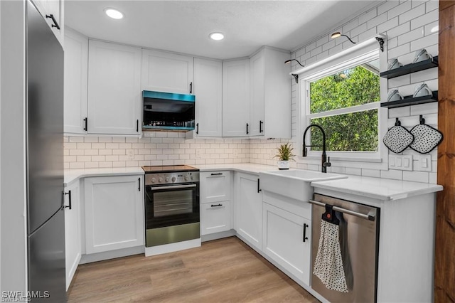 kitchen featuring a sink, white cabinets, appliances with stainless steel finishes, and decorative backsplash