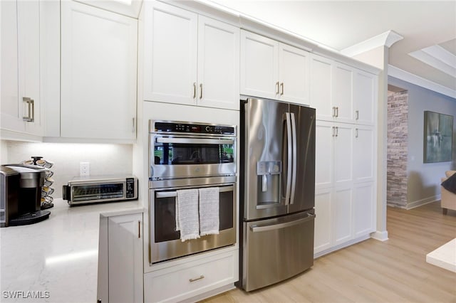 11607 Periwinkle Dr, Naples, FL 34120 - kitchen with a toaster, light stone counters, stainless steel appliances, white cabinets, and light wood-type flooring