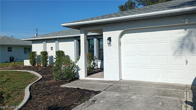 316 SE Santa Barbara Pl, Cape Coral, FL 33990 - property entrance with concrete driveway, a garage, a shingled roof, and stucco siding