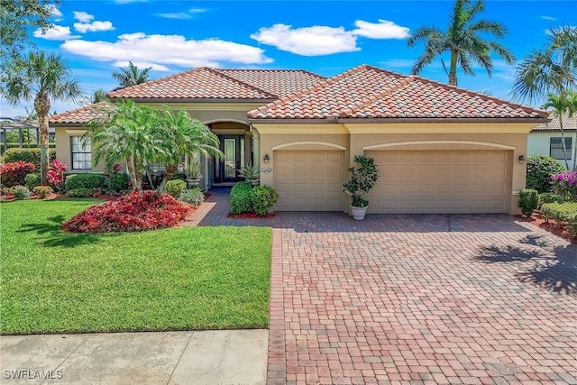 mediterranean / spanish-style home with a tiled roof, stucco siding, decorative driveway, a front yard, and an attached garage