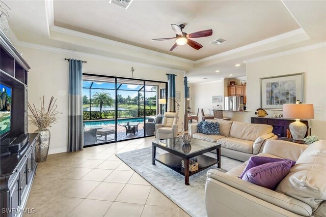 living area with visible vents, a tray ceiling, a ceiling fan, and light tile patterned flooring